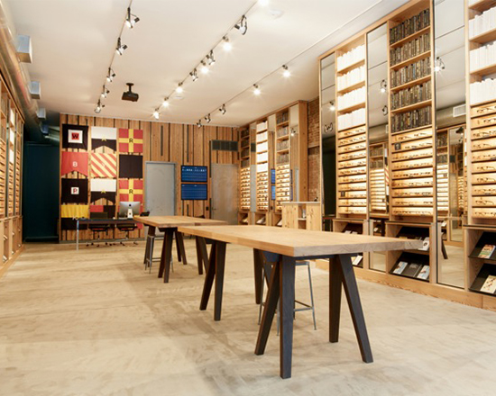 Photograph of solid antique heartpine shelving and tables, mirrors, and integrated lighting produced by Townsend Design for Warby Parker's NYC Meatpacking District retail store project.